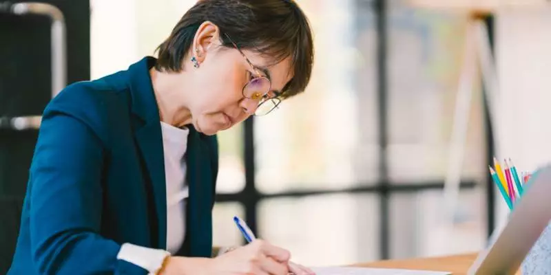 A healthcare administrator sits at a desk and writes in a notebook.