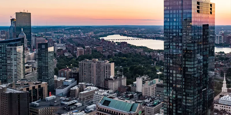 The Boston skyline against a pink and orange sky.