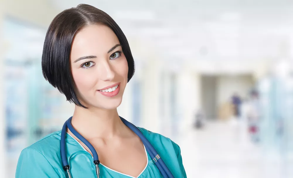 A healthcare professional wearing a stethoscope smiles at the camera.