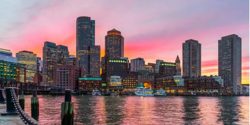 The Boston harbor against a pink and purple sunset.