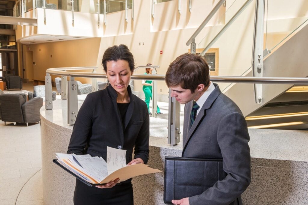 Professional colleagues review documents in a modern office lobby.